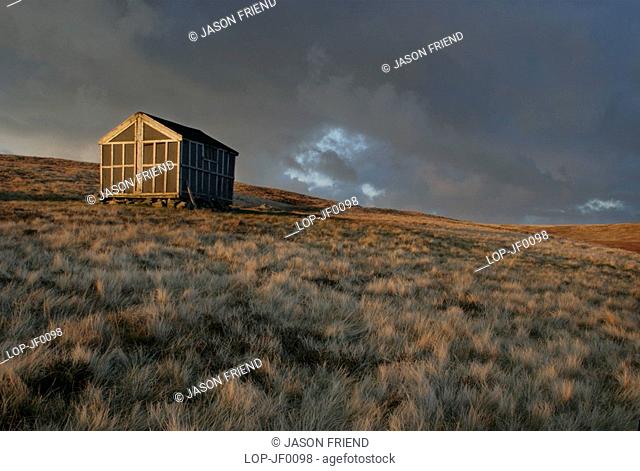 England, Cumbria, Lake District National Park, The setting sun illuminates Lingy Hut which is a welcome sight for hikers on the Cumbria Way track