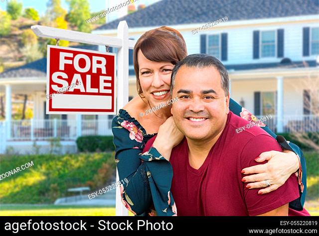 Mixed Race Young Adult Couple In Front of House and For Sale Real Estate Sign
