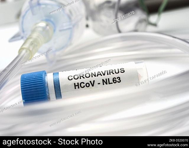 Vial with Sars-cov-2 coronavirus sample next to an oxygen mask in a hospital, conceptual image