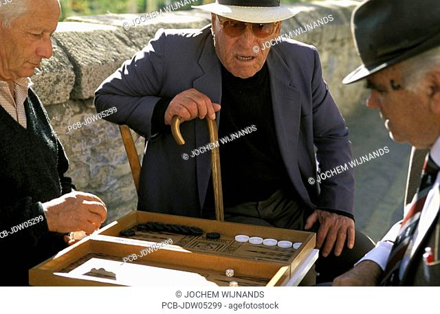 old man watching his friends playing backgammon