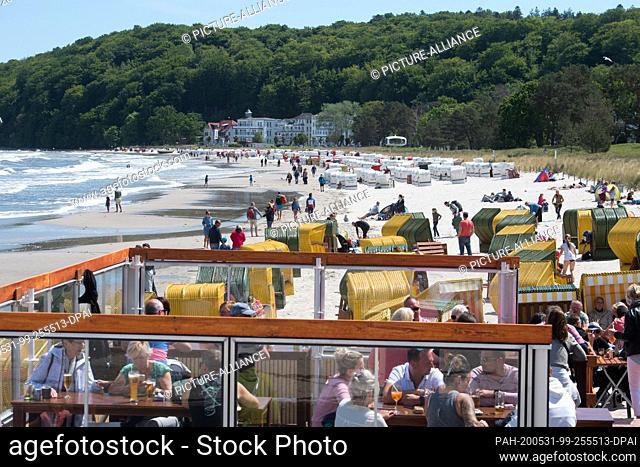 31 May 2020, Mecklenburg-Western Pomerania, Binz: Tourists sit in the wind-protected outer area of a restaurant on the beach