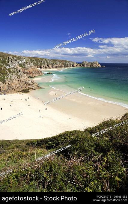 A view of the sandy beach at Porthcurno with Logan rock in the distance