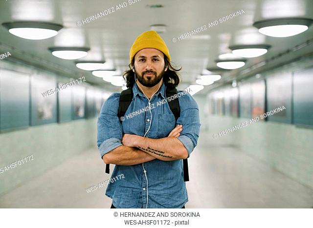 Portrait of bearded man with backpack and earphones in an underpass, Berlin, Germany