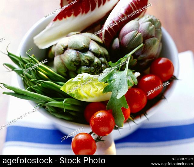 A bowlful of fresh vegetables (tomatoes, beans, artichokes)