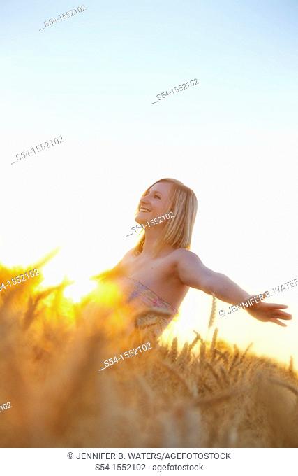 A happy young woman in a field of barley in Lewiston, Idaho, USA