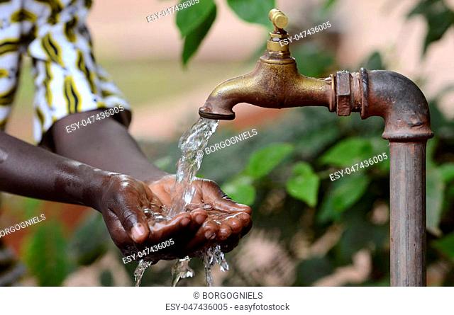 Climate Change Symbol: Handful Of Water Scarsity for Africa Symbol. Hand of an African black boy with water pouring from a tap