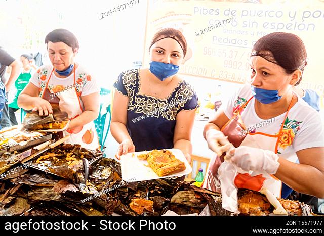 Merida, Mexico - 28 October 2018: Women showing Pibes, traditional chicken corn dish wrapped in banana leafes sold for day of the dead in San Sebastian Park