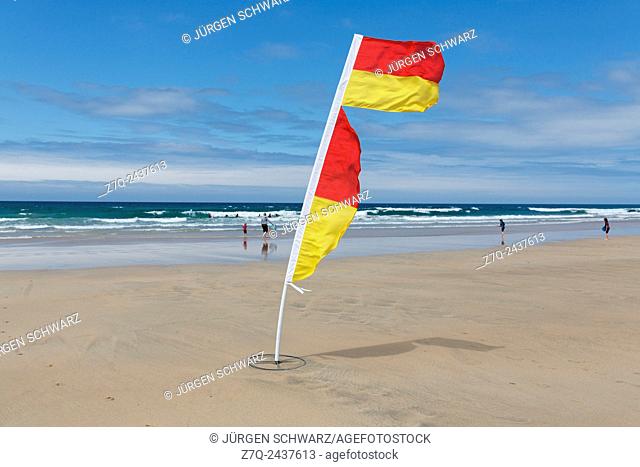 Yellow and red flag of life guards to mark the save part of the fistral beach on a windy day in Newquay, Cornwall, UK