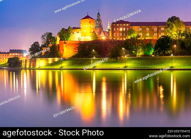Panorama of Wawel Hill with reflection in the river at night as seen from the Vistula, Krakow, Poland