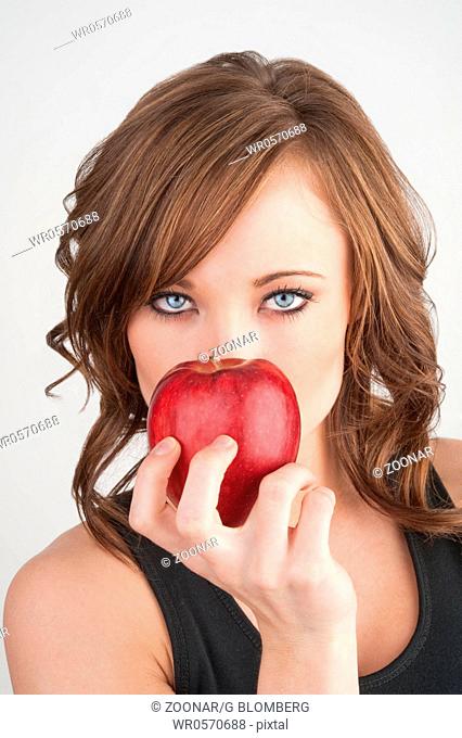 Beautiful girl holding an apple in front of her fa