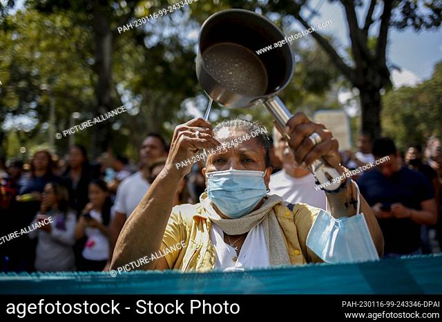 15 January 2023, Venezuela, Caracas: A woman wearing a mouth-nose covering bangs on a cooking pot during a protest by teachers