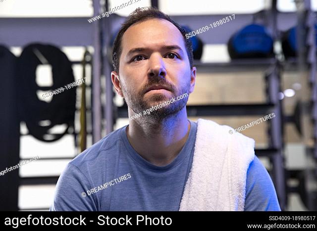 Low angle portrait of man taking a break from workout with towel on his shoulder