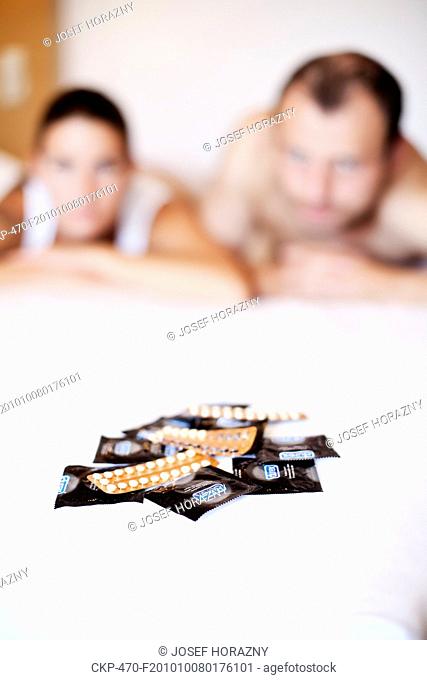 Young woman and young man with contraceptive pills, birth-control pill, condom, blister pack of combined oral contraceptive pills, birth control