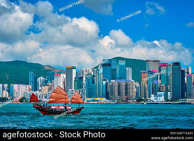 HONG KONG, CHINA - MAY 1, 2018: Hong Kong skyline cityscape downtown skyscrapers over Victoria Harbour in the evening with junk tourist ferry boat on sunset