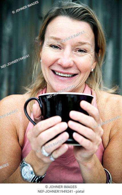 Smiling mature woman with mug, Sweden