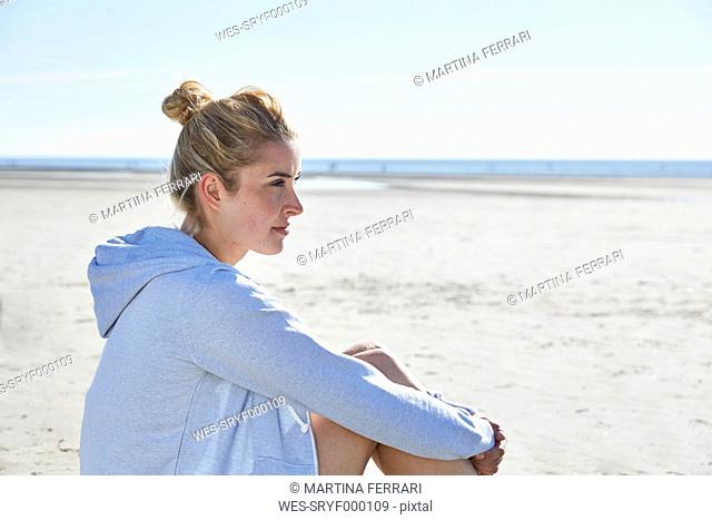 Young woman wearing hoodie sitting on the beach