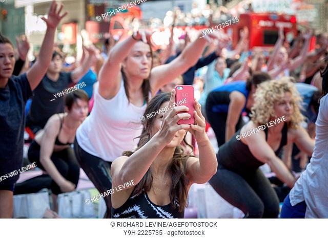 A yoga enthusiast does a ''selfie'' amidst the yoga practitioners in Times Square in New York participating in a Power Yoga class on the first day of summer