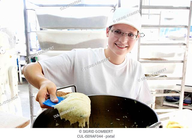 Baker scooping bread dough