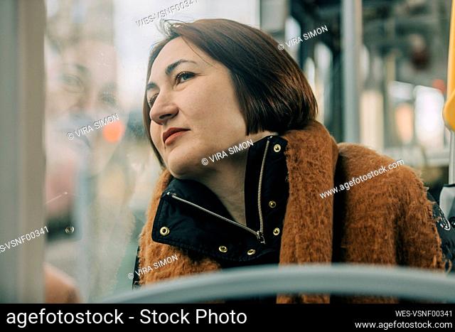 Mature woman looking through window sitting in tram