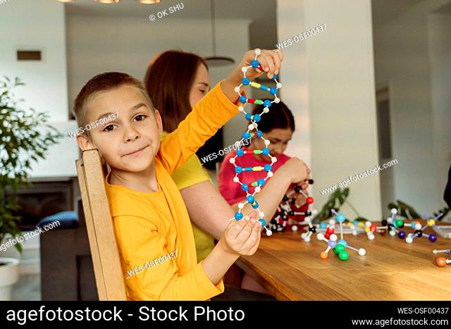 Boy holding helix model by mother at home