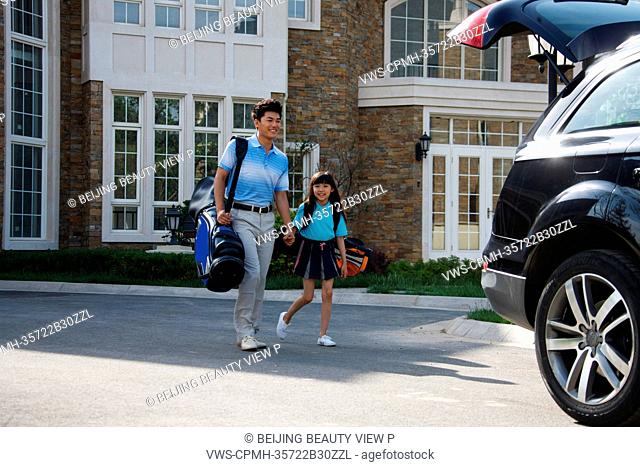 Oriental father taking daughter to car with golf bag