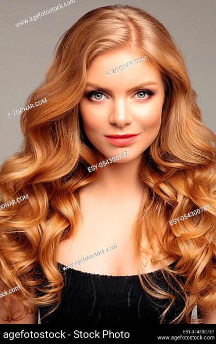 Studio fashion portrait of attractive sensual young woman with long wavy fair hair and blue eyes looking at camera. Natural beauty concept. Caucasian