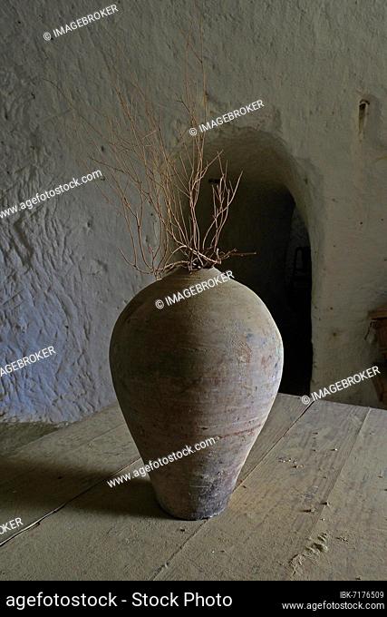 Old clay jug with bare branch in cave house, clay jug on wooden table, vase, clay vessel, cueva, inventory in a cueva, Cuevas del Calguerín