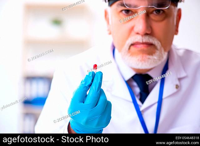 Old expert criminologist working in the lab for evidence