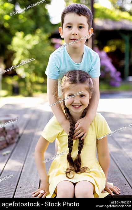 Smiling boy with sister sitting in garden
