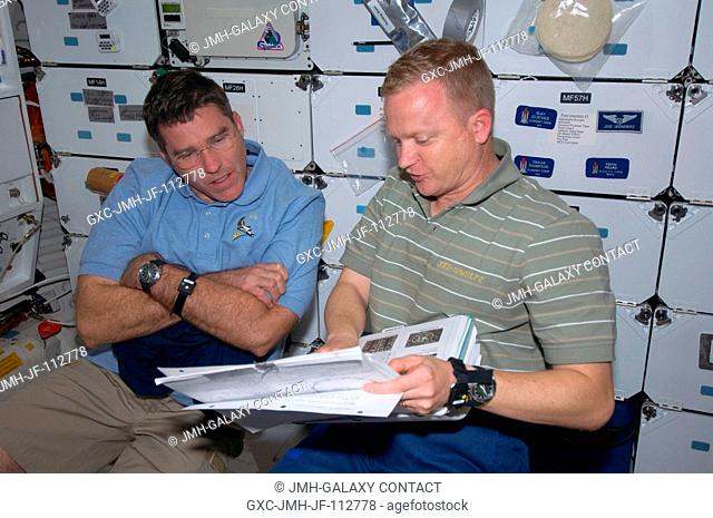 Astronauts Eric Boe (right), STS-126 pilot, and Steve Bowen, mission specialist, look over a procedures manual on the middeck of Space Shuttle Endeavour while...