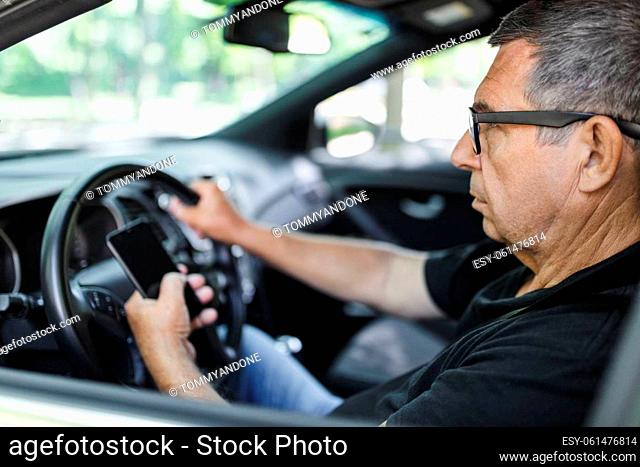 Active senior in his 70s driving a car and usig his mobile phone