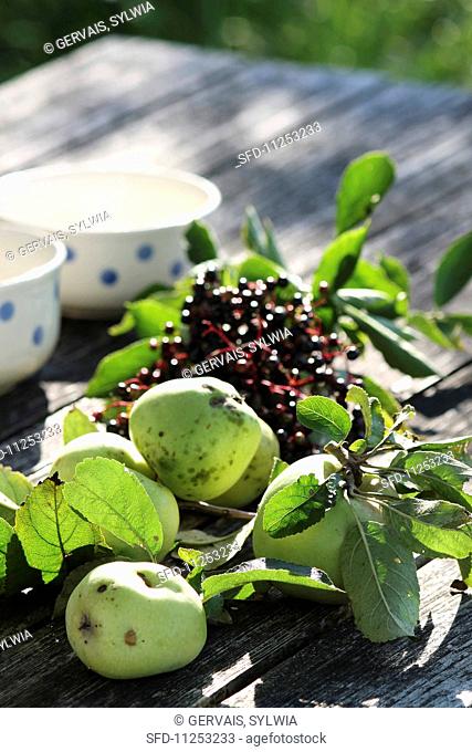 Green apples and elderberries on a wooden table