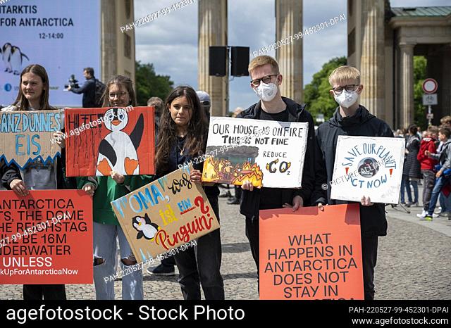 27 May 2022, Berlin: At a rally for the protection of Antarctica, participants hold placards in front of the Brandenburg Gate