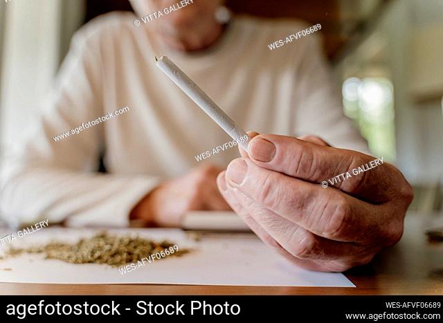 Close-up of senior man holding marijuana joint at home