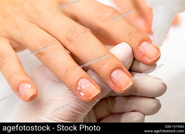 Manicure process in a beauty salon. Hands of the master in sterile gloves polished nails client