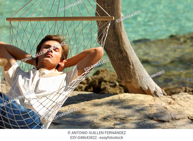 Relaxed man resting on a hammock on the beach on summer vacation