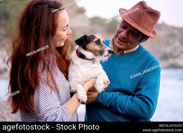 Man and woman playing with pet dog