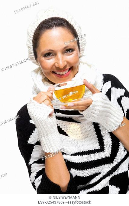 young brunette woman with white wool hat drinking a cup of tea to warm up isolated on white background