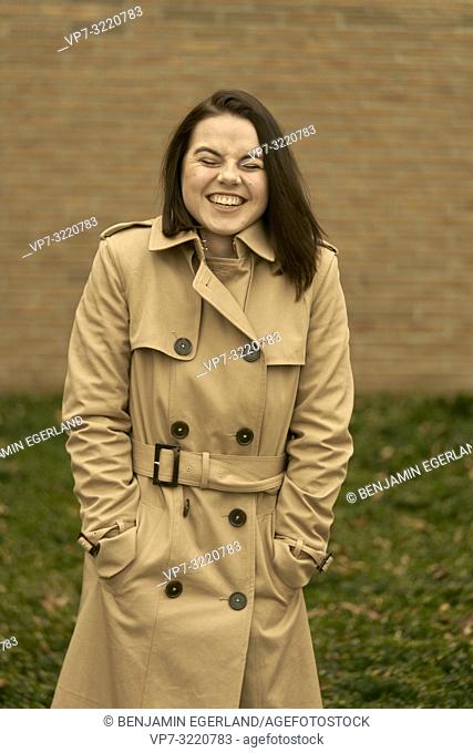young happy laughing woman outdoors in city park during autumn season, wearing coat, candid emotion, closed eyes, pure happiness, in Munich, Bavaria, Germany