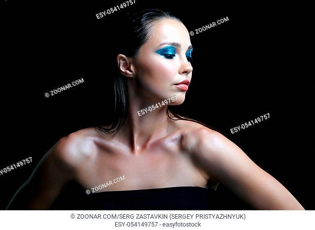 Beauty portrait of female on black background. Woman with evening beauty makeup on black background. Girl with perfect skin and blue-green smoky eyes eye...