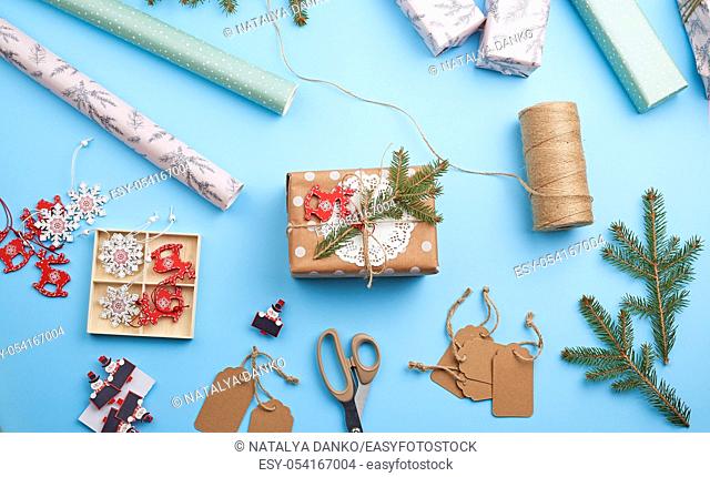 roll of pink wrapping paper, decor, spruce branches, Christmas toys and boxes with gifts on a blue background, top view. Christmas holiday concept