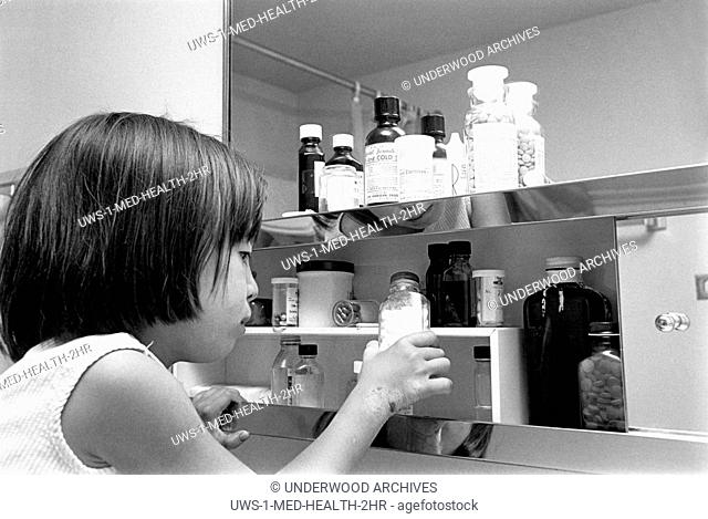 United States: 1967.A young girl looking at over the counter and prescribtion drugs in a medicine cabinet