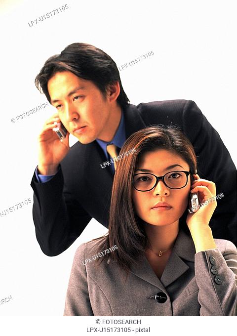 Businessman and businesswoman using mobile phone, Front View