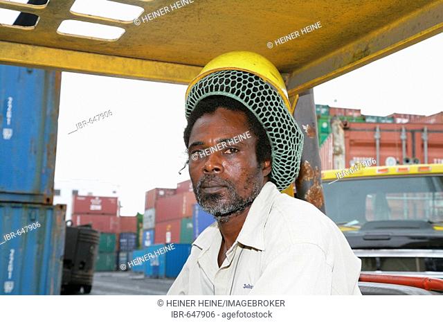 Dock worker wearing hardhat over pinned-back dreadlocks at John Fernandes transshipment port in Georgetown, Guyana, South America