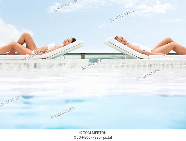 Women sunbathing in lounge chairs at poolside
