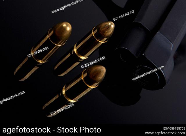 Gold bullets and gun on black background