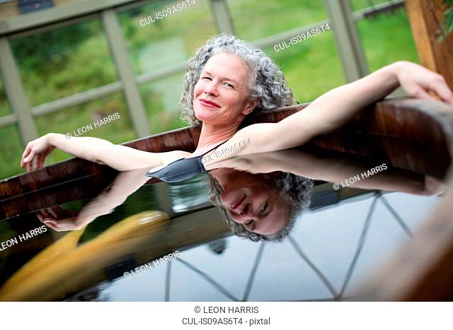 Portrait of mature woman relaxing in hot tub at eco retreat
