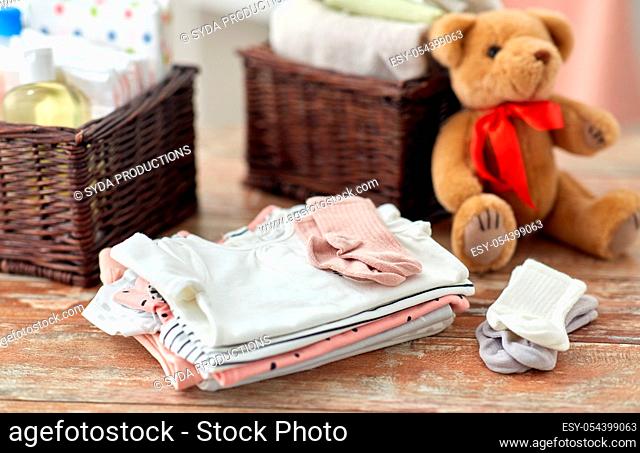 baby clothes and teddy bear toy on table at home