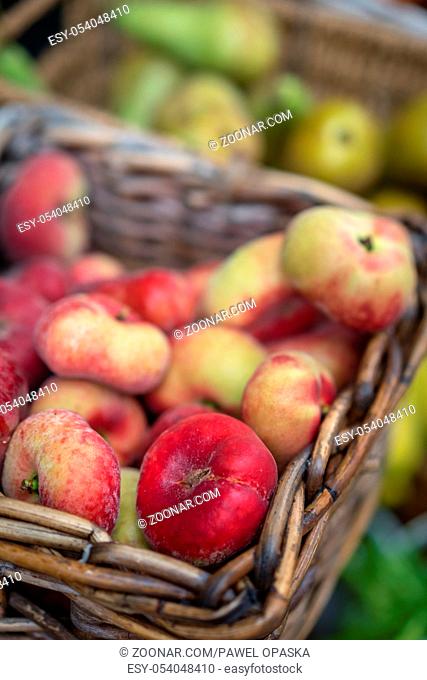 Nectarines and pears in wicker basket on display on a stall at farmers market in Cornwall, Uk