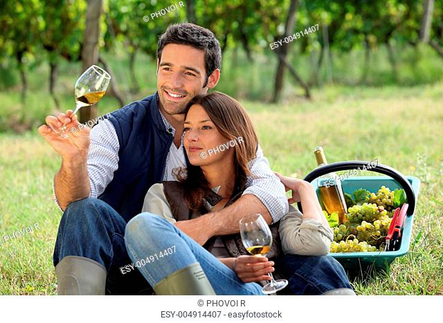 Couple enjoying a bottle of wine whilst harvesting grapes